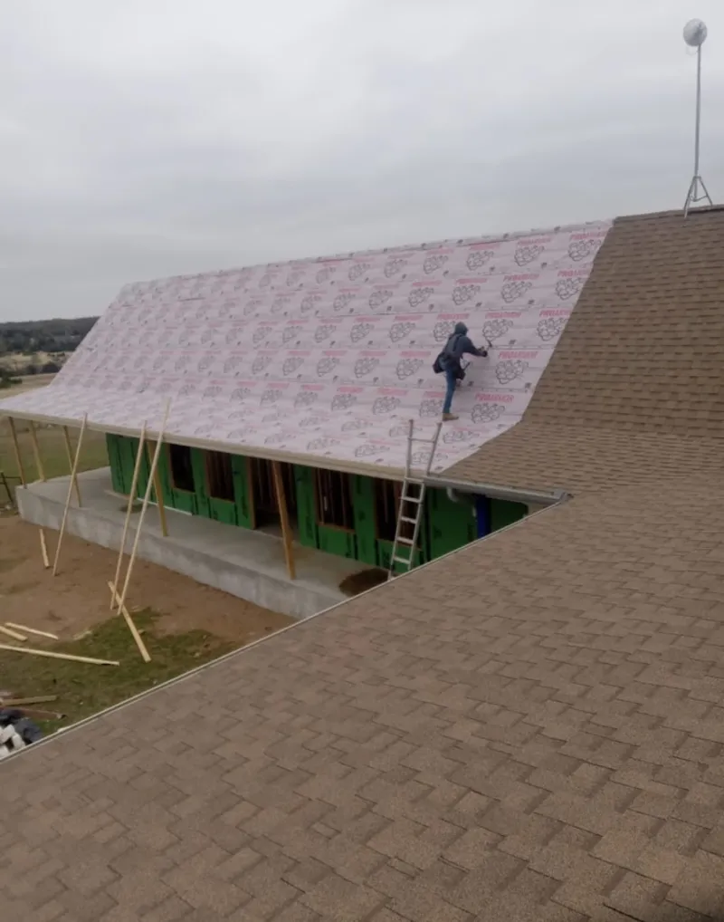 Worker preparing underlayment for a metal roof installation in Nacogdoches